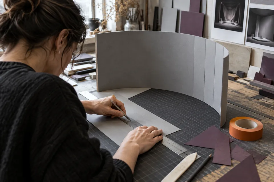 Model board being cut and folded at a workbench